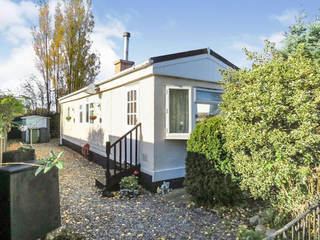 This detached park home features one bedroom, shower room, front and rear gardens and is close to village amenities like a post office, restaurants, pharmacies and hairdressers. This property was first listed on 6 November, and was reduced on 26 December by £10,000. It is currently available for offers over £40,000.