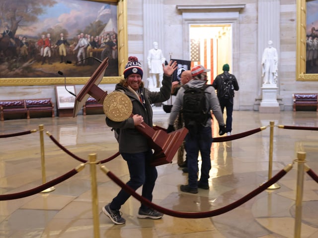 A rioter makes off with a podium.