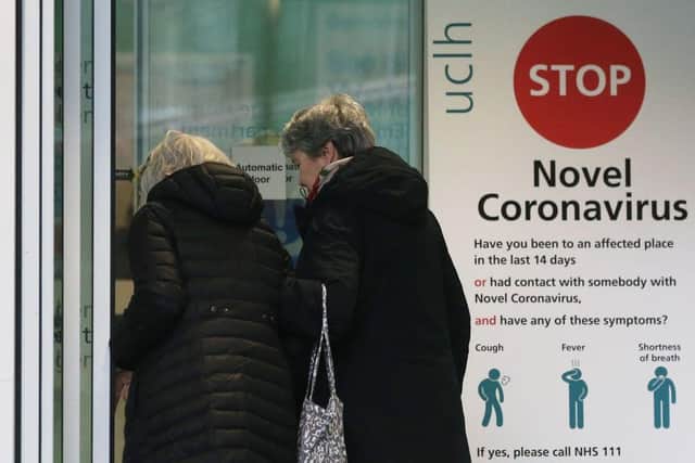 Two women walk past a sign providing guidance information about novel coronavirus (COVID-19) (Photo by ISABEL INFANTES/AFP via Getty Images)