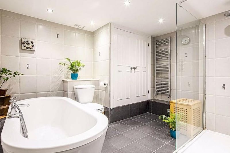 The lower ground floor bathroom has a white suite with a separate walk-in shower enclosure and a cupboard which has plumbing for a washing machine.