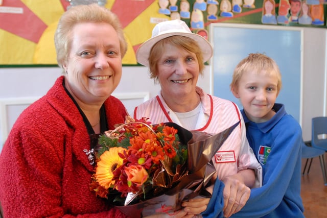Albert Elliott Primary School head teacher joins pupil Kieran Wilson in presenting Kathleen Angus with flowers after her 34 years of service as a dinner lady in 2006.