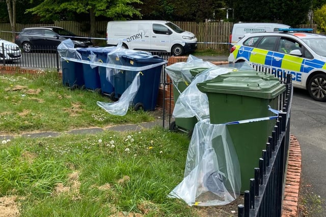 A police vehicle parked near the sealed-off bins
