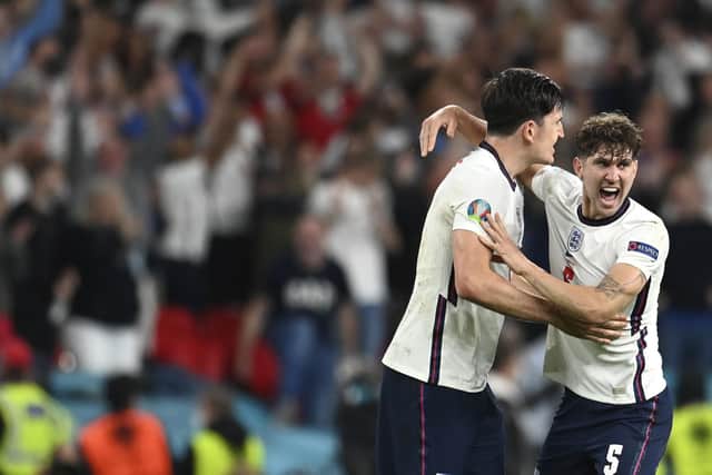 England's John Stones, right, celebrates with Harry Maguire, center, after winning the Euro 2020 semi final against Denmark at Wembley. (Andy Rain/Pool via AP)