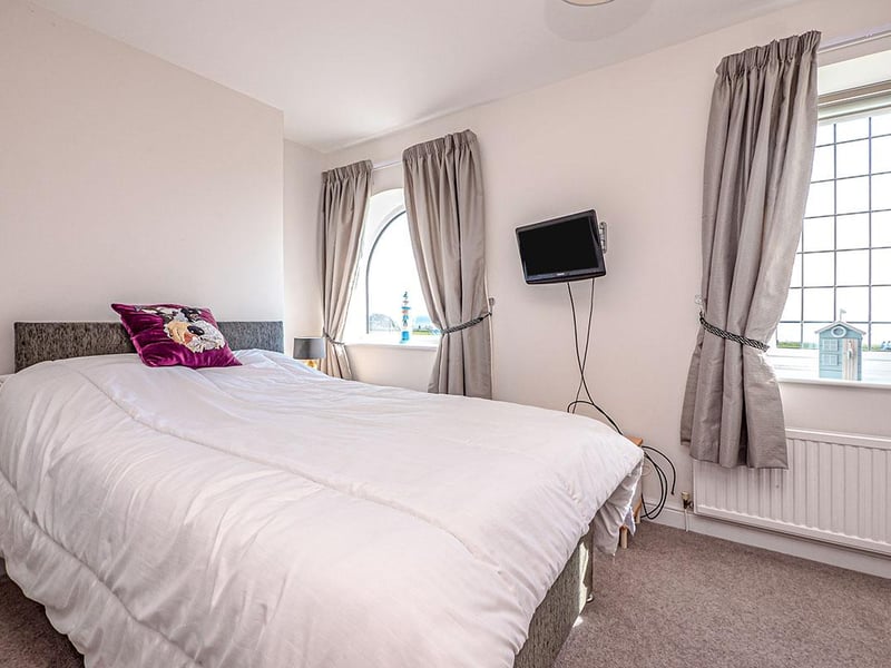 A front-facing, double bedroom with two windows to the front, one being a decorative arched window, both offering unbeatable sea views.