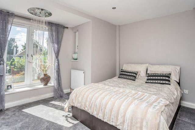 This bedroom is modern and lets in a lot of natural light, offering views of the garden