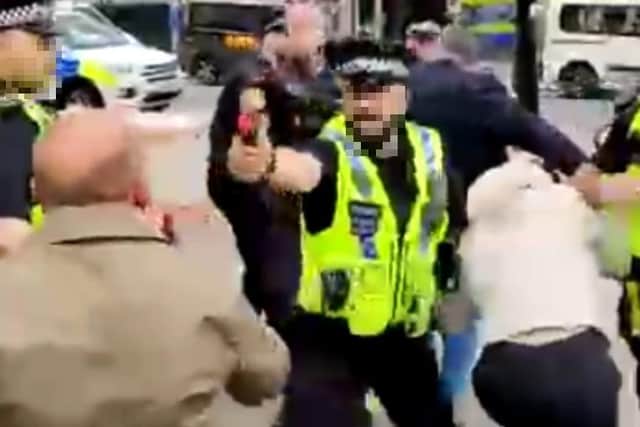 A policeman aims pepper spray after trouble broke out at the rally at the Town Hall on Sunday