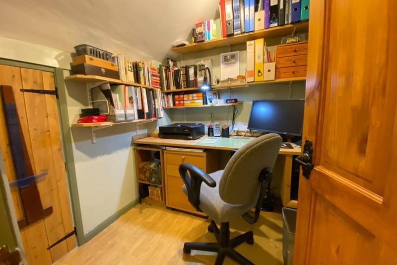 Bedroom four is currently used as a study and has a range of built-in office furniture and wall-mounted shelving. A low-level door opens to reveal a storage area.