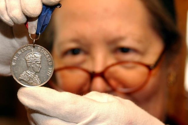Volunteer Sue Lindley holding up a medal with King George VIII. Taken in 2005.