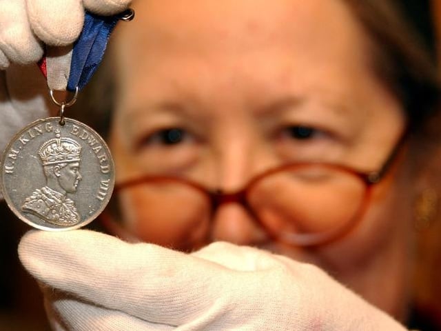 Volunteer Sue Lindley holding up a medal with King George VIII. Taken in 2005.