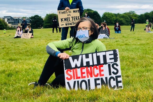 A peaceful activist sitting with her 'white science is violence' placard at the Black Lives Matter protest in Edinburgh which saw thousands descend on Holyrood Park