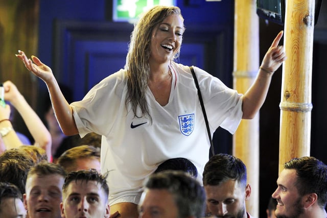 An England fan sits on the shoulders of a friend to watch the match in 2018