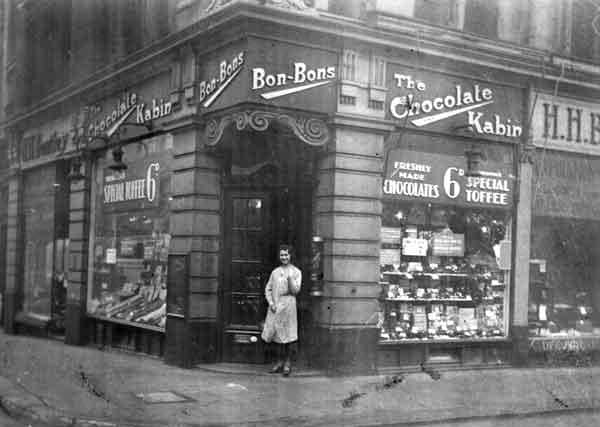 The very first Thorntons shop, the Chocolate Kabin, was opened in October 1911 in Sheffield by travelling confectioner Joseph William Thornton. 
Pictured is shop assistant Ivy Clow (later Yates) outside Thornton's Chocolate Kabin on the corner of Howard Street and Union Street, 1920.