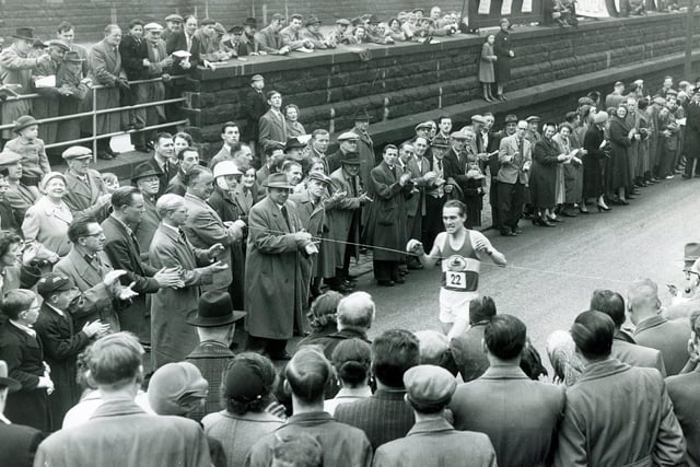 Amidst cheering crowds, No. 22, A P Keily, comes in to win the Sheffield Telegraph's 12th annual Easter Marathon from Doncaster to Sheffield... April 1957