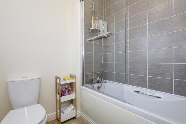 The second look at the family bathroom reveals a panelled bath with a wall-mounted electric shower. The walls are partially tiled and there is also an extractor fan with a uPVC double-glazed, opaque window to the back of the house.