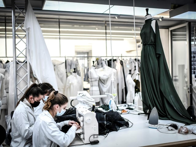 Seamstresses work on couture garments