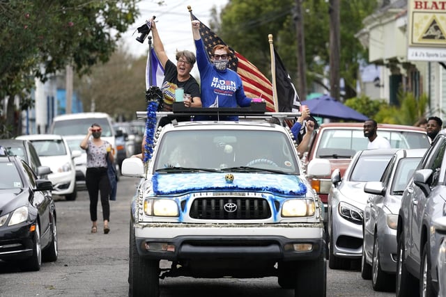 People celebrate as a truck festooned with Biden Harris decorations drives through the Bywater section of New Orleans. (AP Photo/Gerald Herbert)