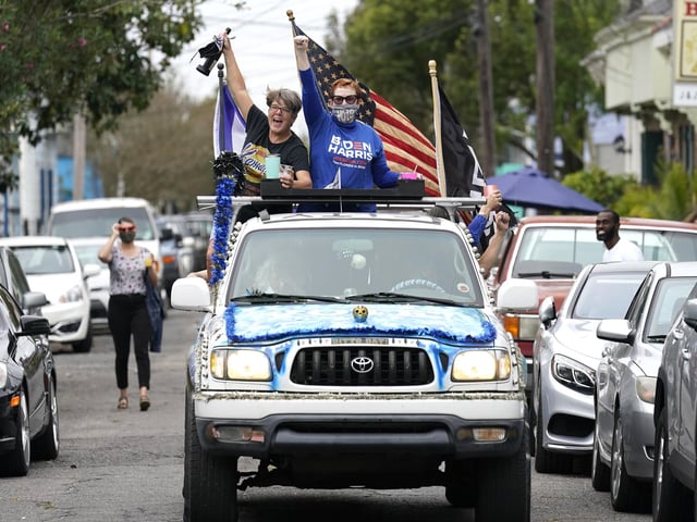 People celebrate as a truck festooned with Biden Harris decorations drives through the Bywater section of New Orleans. (AP Photo/Gerald Herbert)
