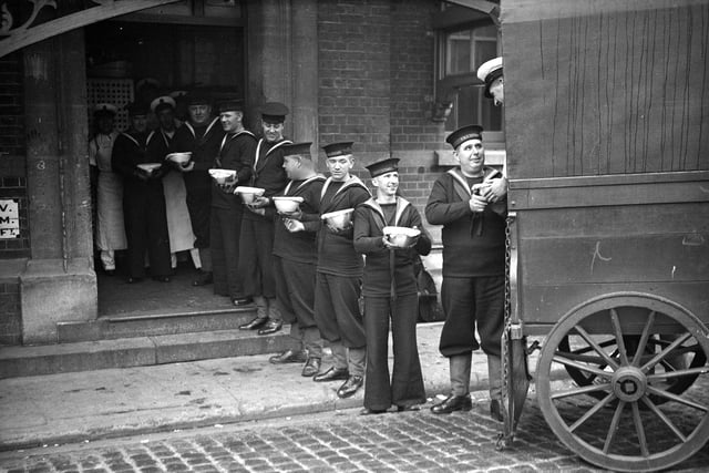 13th December 1933:  A line of sailors at the Royal Naval barracks at Portsmouth pass Christmas puddings to their comrades from the back of a wagon.  (Photo by PNA Rota/Getty Images)
