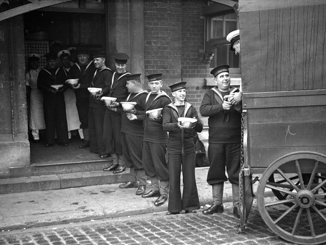 13th December 1933:  A line of sailors at the Royal Naval barracks at Portsmouth pass Christmas puddings to their comrades from the back of a wagon.  (Photo by PNA Rota/Getty Images)