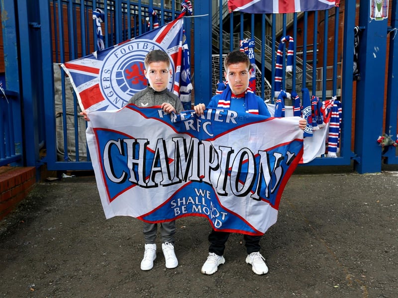 Rangers fans wearing Steven Gerrard masks hold up a banner outside of the Ibrox Stadium, home of Rangers FC.
