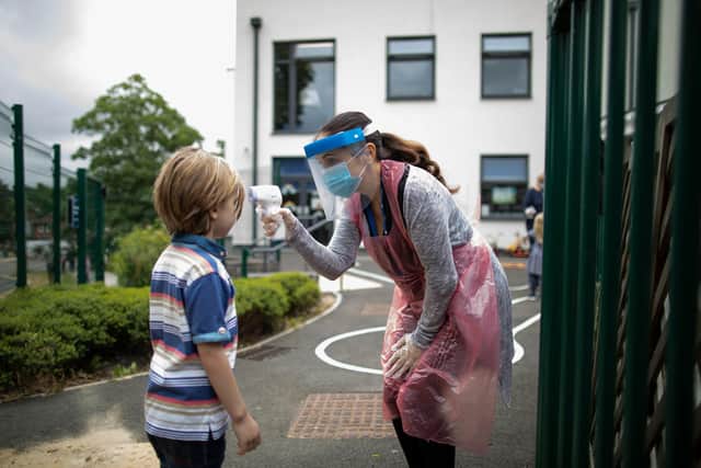 A member of staff wearing personal protective equipment (PPE) takes a child's temperature (Photo by Dan Kitwood/Getty Images)