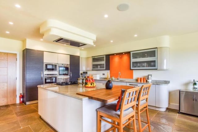 The property boasts a spacious kitchen with a natural stone floor, built in microwave and oven alongside a gas hob on the granite worktop island.