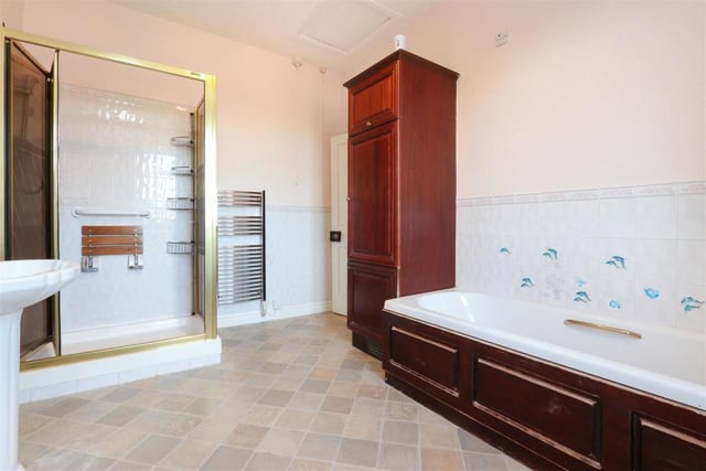 Mahogany coloured cupboard and bath surround are in contrast to the white suite.