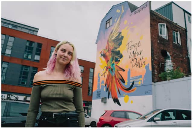 Street artist Megan 'Peachzz' Russell next to her mural of the parrot in August 2022.