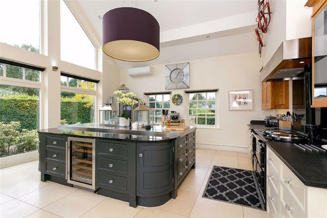 The stylish and modern kitchen is equipped with fitted cupboards and appliances, with an open plan dining area and a central island.