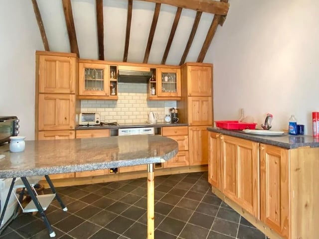 Moving into the annexe now, and this kitchen is fitted with a range of wall and base units, plus a work surface, sink and drainer. With ceramic tiled flooring and a fitted storage cupboard, there is space and plumbing for a washing machine, dishwasher and tumble dryer.