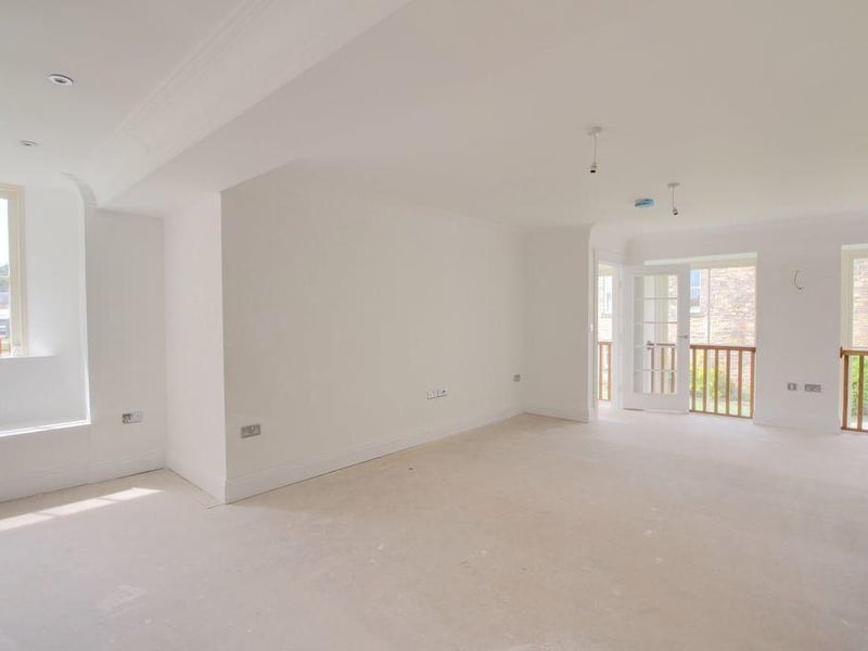 Adjoining the kitchen and part of an open-plan first floor is this expansive living area. There are windows to the side.