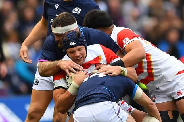 Japan's flanker Pieter Labuschagne (C) is tackled during the Autumn International friendly rugby union match between Scotland and Japan at Murrayfield Stadium in Edinburgh on November 20, 2021. (Photo by ANDY BUCHANAN/AFP via Getty Images)