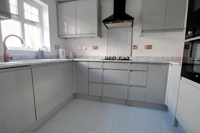 The kitchen is fitted with grey wall and base units, a complementary roll edge worktop incorporating a sink with mixer tap and a range of fitted appliances including electric fan assisted oven, gas hob with extractor above, microwave, fridge/freezer and dishwasher.
