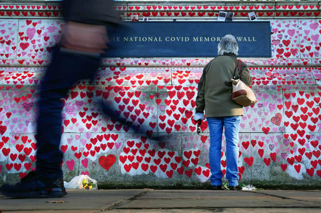 A woman pauses to look at dedications written on the National Covid Memorial Wall