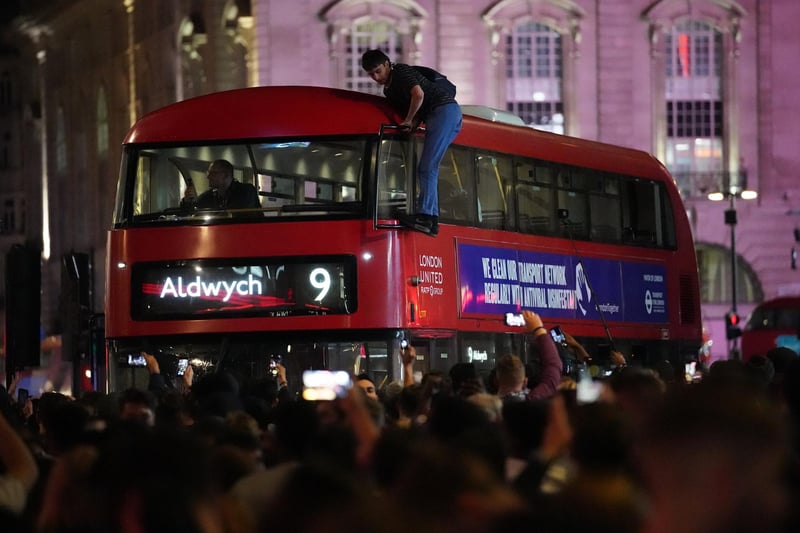 A man climbs the outside of a bus whilst England fans celebrate in Piccadilly Circus, central London.