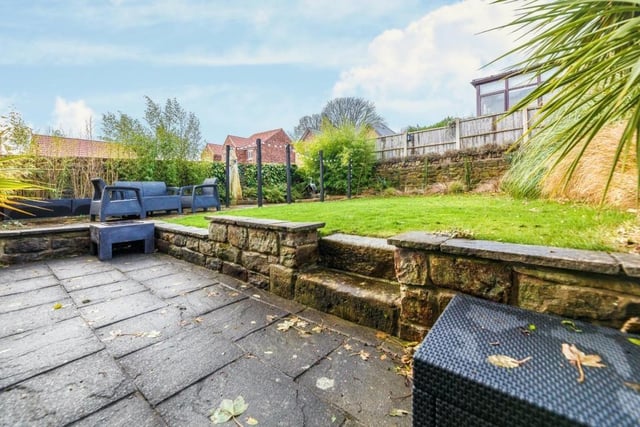 At the back of the house is a large landscaped garden, featuring a stone flagged patio seating area.