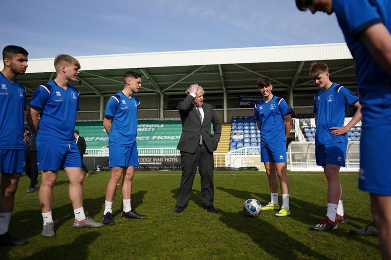 Britain's Prime Minister Boris Johnson (C) speaks with players from the youth team during a visit to Hartlepool United Football Club as he campaigns on behalf of Conservative Party candidate Jill Mortimer in Hartlepool, north-east England on April 23, 2021, ahead of the 2021 Hartlepool by-election to be held on May 6.