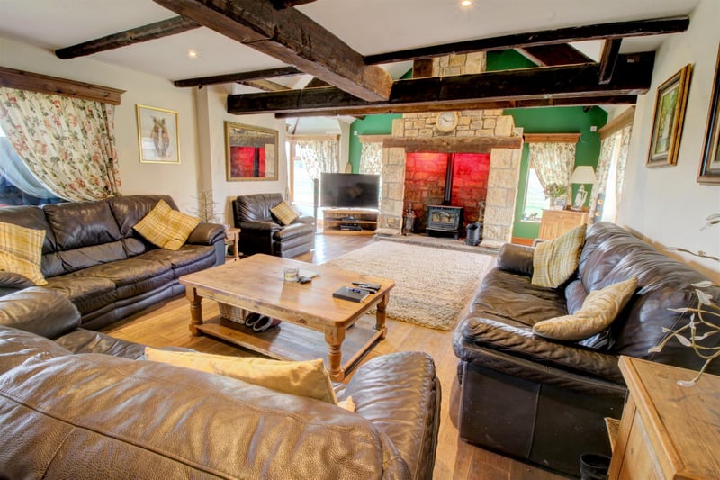 The main lounge which is brimming with character by way of its wood flooring along with exposed beams and trusses. A magnificent floor-to-ceiling stone inglenook fireplace takes pride of place and a multi-fuel wood burner sits proudly within.