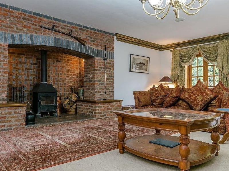 The hallway leads to this large sitting-room. It boasts some epic, exposed brickwork, wooden beams and an Inglenook fireplace and wood burner.
