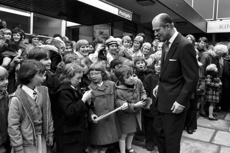 Prince Philip  stops to chat to a little girl whose camera isn't working when he visited the Kingdom Shopping Centre in Glenrothes in October 1976.