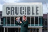 Tedd George with a copy of Stirring Up Sheffield outside the Crucible Theatre