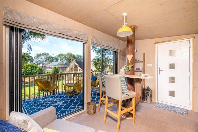 The tree house has been transformed into a cosy modern living space, with a sofa, dining table and balcony which overlooks the rest of the garden.