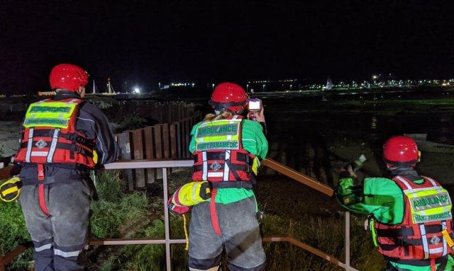 Paramedics from SCAS watch on as a rescue operation to reach two women stuck in mud in Hilsea is carried out.