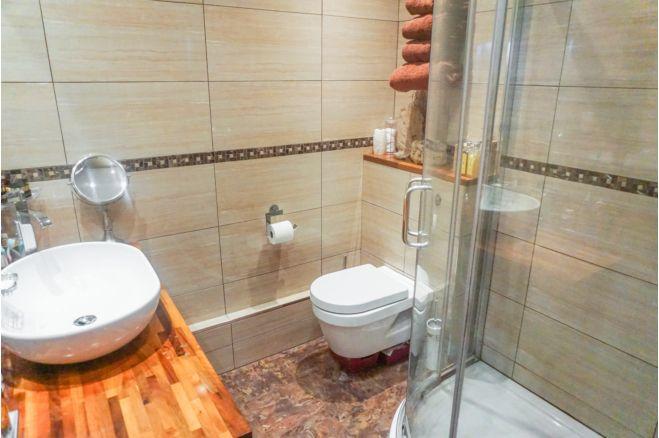 This bathroom features a walk-in shower. There is also a lovely sink and tasteful tiling.