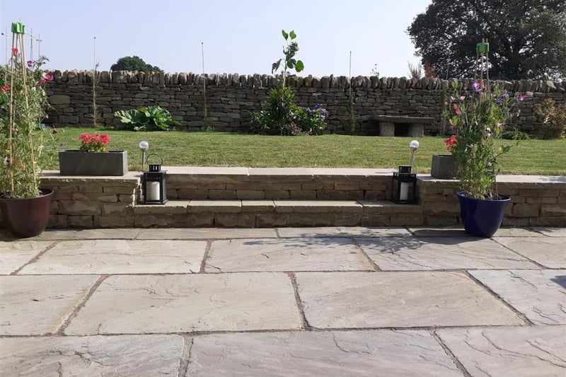 Generous landscaped rear garden with dry stone boundary walls.
