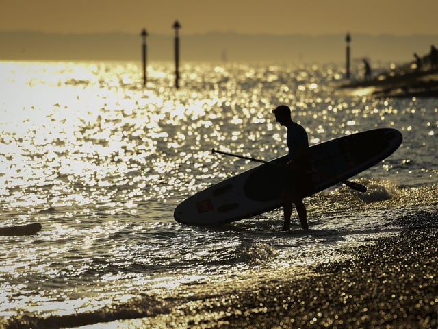 A stand up boarder enters the sea in the evening sunshine on Southsea beach taken by Finnbarr Webster/Getty Images.