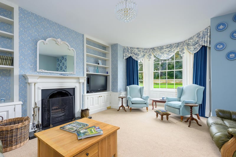 The cosy living room benefits from a large stone fireplace at its heart, with wonderful views over the garden from the bay windows and plenty of seating space.