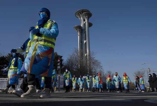 Volunteers walk by the Olympic Tower to take up positions just outside the Beijing National Stadium, or Birds Nest, before the Opening Ceremony of the Beijing 2022 Winter Olympics: Kevin Frayer/Getty Images