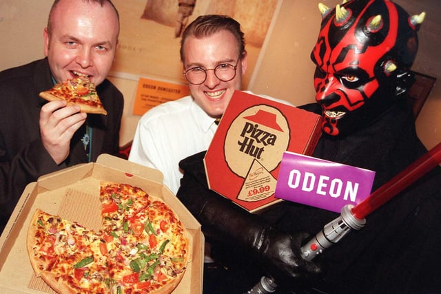 Doncaster Odeon general manager Iain Porter tucks into a Pizza Hut pizza, watched by Gordon Irving, manager of the Pizza Hut in High Street, Doncaster, and Star Wars character Darth Maul in 1999
