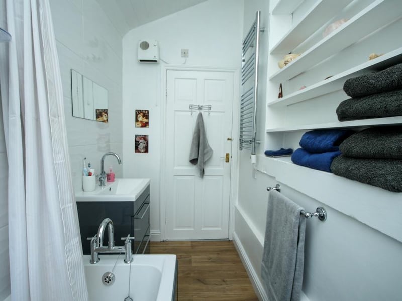 Part-tiled walls, tiled flooring, electric towel rail, inset shelving, upvc double-glazed window to the side elevation.